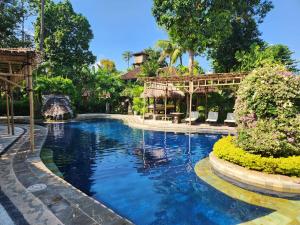 a swimming pool in a resort with trees and bushes at Rambutan Hotel in Lovina