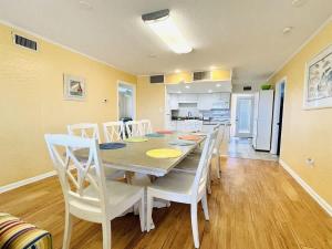 ein Esszimmer mit einem Tisch und weißen Stühlen in der Unterkunft OCEANFRONT HOUSE ON THE SAND 2 Kings 4br 4ba 1st Floor of Triplex SLEEP 12 PGP1 in Myrtle Beach