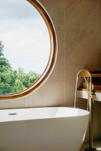 Una bañera en un baño con ventana redonda. en Blue Horizon Haad Yao, Seaview 3BR Apartment 1st Floor, en Ko Pha Ngan