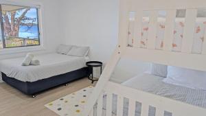 a small bedroom with a bunk bed and a window at Billyz Basin by Experience Jervis Bay in St Georges Basin +6 photos