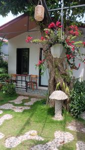 a garden with a bench and a tree with flowers at Tran Chau Garden Home in Cat Ba