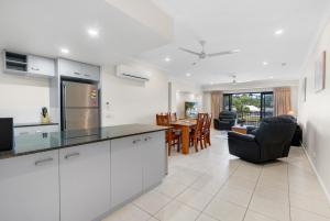 una cucina con mobili bianchi e un soggiorno di Bright 3-Bedroom Beachside Stay with Pool & BBQ a Trinity Beach