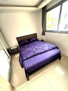a purple bed in a room with a window at Modern 1-Bedroom Condo with Pool View Arcadia Beach Continental Pattaya in Pattaya South