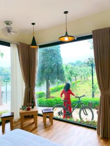 a woman walking a bike in a room with a large window at An Garden Villa - Venuestay in Sơn Tây