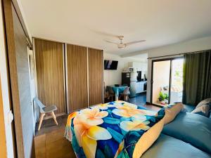 a bedroom with a bed with a flower blanket on it at Tehautahi Cozy Lodge 1 in Papeete