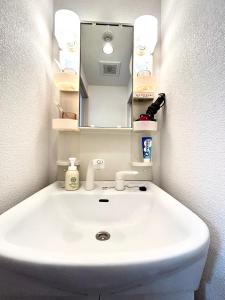 a bathroom with a white sink and a mirror at 关西机场直达 i Home Osaka URBAN NOOK 舒适双床房 天下茶屋站步行3分钟 in Osaka +11 photos