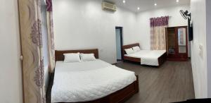 a bedroom with two beds with white sheets and wooden floors at Nhà nghỉ Tứ Hải in Sa Vi Xom