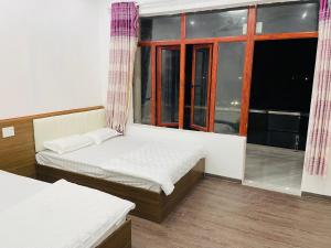 two beds in a room with a window at Nhà nghỉ Tứ Hải in Sa Vi Xom +1 photo