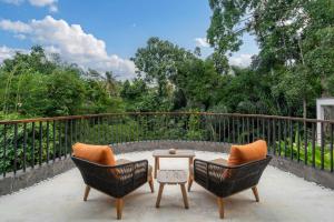 a patio with two chairs and a table on a balcony at Villa Gayatri Sindu by BaliSuperHost in Ubud