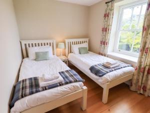 two beds in a small room with a window at Mell View Cottage in Watermillock