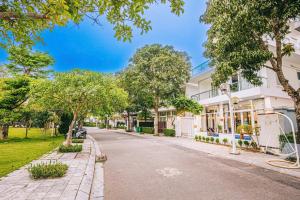 a street in front of a white building with trees at Villa Sao Biển 96 FLC Sầm Sơn in Sầm Sơn