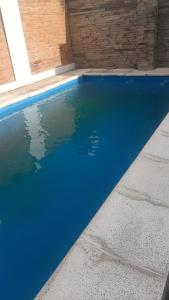 a blue swimming pool with a brick wall at Daiana Carlos temporarios in Estación Guadalupe