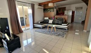 a living room with couches and a table at Maison de charme proximité ville in Saint-Joseph +6 photos