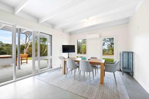 a dining room with a table and chairs and windows at Yarra Valley 2BR Lux Vineyard Retreat in Dixons Creek