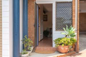 an open door of a house with potted plants at Spooky Beach Lodge - Oceanstays in Yamba