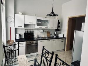 a kitchen with white cabinets and a table and chairs at DG City-Apartment in Spremberg