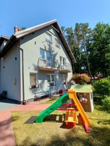 a playground in front of a house with a slide at Dom Gościnny Sówka in Pobierowo