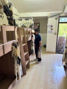 a man holding a bucket in a room with shelves at Panda Lodge Home Stay in Bangkok