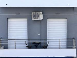 ein Balkon mit zwei Fenstern und einem Ventilator an einem Gebäude in der Unterkunft krya suites in Livadia