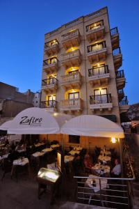 a building with a restaurant with tables in front of it at Hotel San Andrea in Xlendi