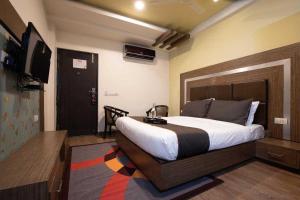 a bedroom with a large bed and a television at Hotel O JLN Stadium Ernakulam Formerly Peediyal Tower in Cochin