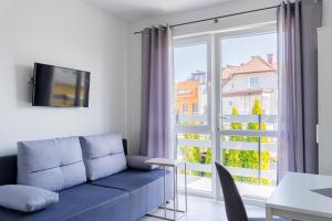 a living room with a couch and a large window at Leśny Karwia - Pokoje 70m od Plaży in Karwia