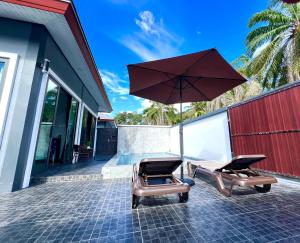 two chairs and an umbrella on a patio at Vina Villa At Krabi in Ao Nang 