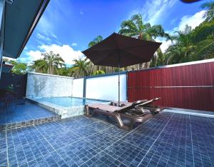 a patio with an umbrella and a swimming pool at Vina Villa At Krabi in Ao Nang 
