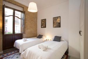 a room with two beds with white sheets and a window at Apartments Carmen III in Valencia