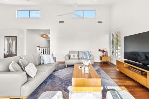 Una sala de estar con un sofá y un televisor. en The Corlette Beach Retreat, en Corlette