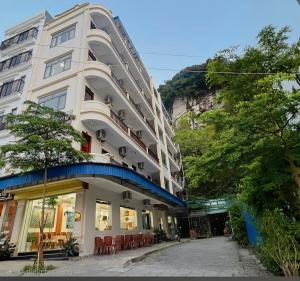 a tall white building with a restaurant in front of it at GOLDEN LAND HOTEL in Cat Ba