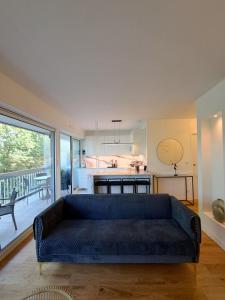 a living room with a blue couch and a kitchen at La Croisette Côté Lac in Créteil