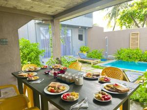 a table with plates of food on it next to a pool at Villa Sea Queen in Ambalangoda