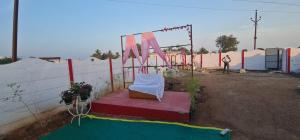 a chair sitting on a stage next to a fence at Farm House With Swimming pool, Celebration area Below 5000 yadagirigutta Hyderabad in Wasalmari +1 photo