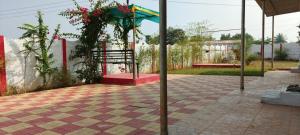 a patio with a table and an umbrella and flowers at Farm House With Swimming pool, Celebration area Below 5000 yadagirigutta Hyderabad in Wasalmari