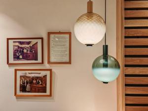 two lights are hanging on a wall with pictures at Hotel Alpenblick in Sarntal