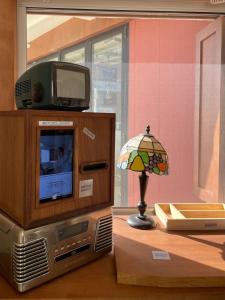 Un televisor en un mueble con una lámpara en una habitación. en OhHey, en Busan