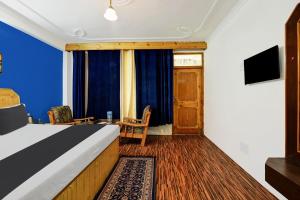 a room with a bed and a tv and a table at Asha Cottage in Manāli