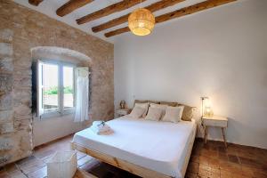 a bedroom with a white bed in a brick wall at Mas Piarnau in Vilasacra