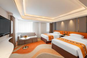 a hotel room with two beds and a flat screen tv at Hotel Beverly Plaza in Macau