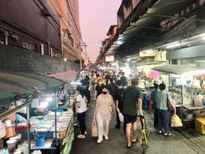 a crowd of people walking through an outdoor market at Bang Chak Studio in Bangkok