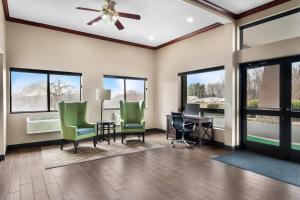 a living room with a ceiling fan and green chairs at Comfort Inn & Suites North East in North East