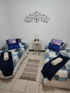 zwei Betten in einem Zimmer mit blauen Kissen in der Unterkunft DE SWARTE MOSSEL in Hondeklipbaai