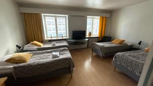 a hotel room with two beds and a television at Lentävä Kalakukko -Veturi B&B in Kuopio