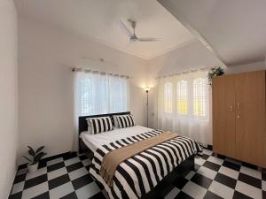 a bedroom with a bed and a black and white checkered floor at Sooru in Mysuru in Mysore