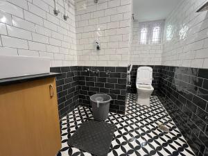a bathroom with a toilet and a black and white tiled floor at Sooru in Mysuru in Mysore