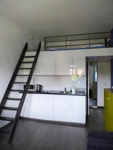 kuchnia z białymi szafkami i łóżkiem na podwyższeniu w obiekcie Room Tour Lubomirskiego 23 w Krakowie