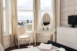 a room with a mirror and a bed and a window at Nethway Hotel in Torquay
