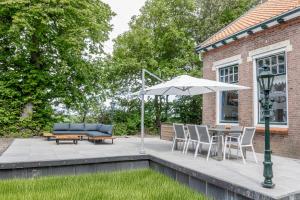 a patio with a table and an umbrella at Huize Adriana in Wolphaartsdijk