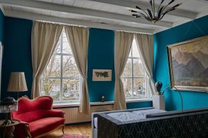 GoedereedeB&B Röderhaus Guesthouse Goedereede的带红色椅子和窗户的蓝色卧室